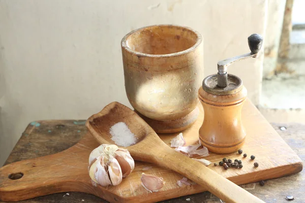 Ahşap harç, bir kaşık ve bir el ile değirmen, baharat, tuz ve garli — Stok fotoğraf