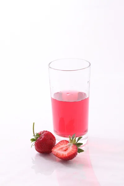 Juice from a fresh strawberry in a transparent glass on a white — Stock Photo, Image