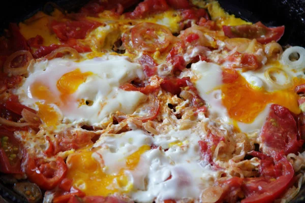 Uova fritte con pomodori e cipolle in una padella di ghisa — Foto Stock