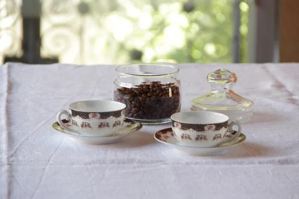 Kaffee in Körnern in transparenter Bank und Kaffeepaar — Stockfoto