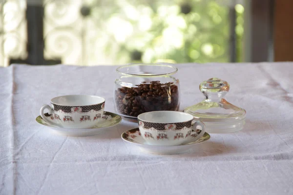 Kaffee in Körnern in transparenter Bank und Kaffeepaar — Stockfoto