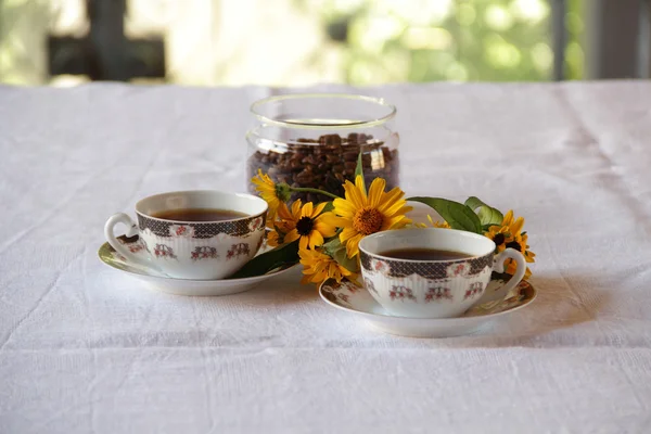 Coffee in coffee cups and a bunch of flowers — Stock Photo, Image