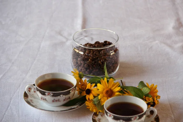 Café em xícaras de café e um buquê de camomilas amarelas — Fotografia de Stock