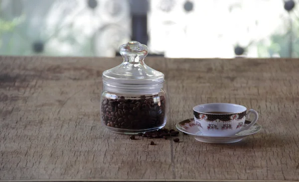 Grains de café en banque transparente et une tasse de café — Photo