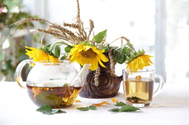 Çay şeffaf bir çaydanlık ve ayçiçeği bir buket