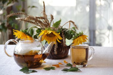 Çay şeffaf bir çaydanlık ve ayçiçeği bir buket