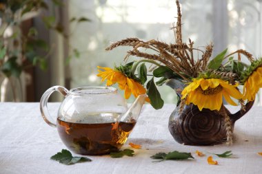 Çay şeffaf bir çaydanlık ve ayçiçeği bir buket