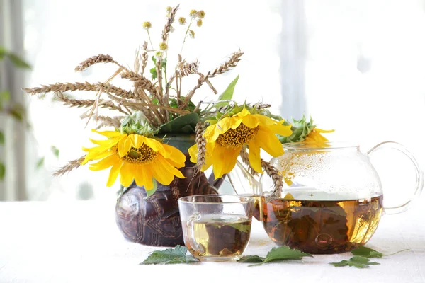 Чай у прозорому чайнику та соняшниках у керамічній вазі — стокове фото
