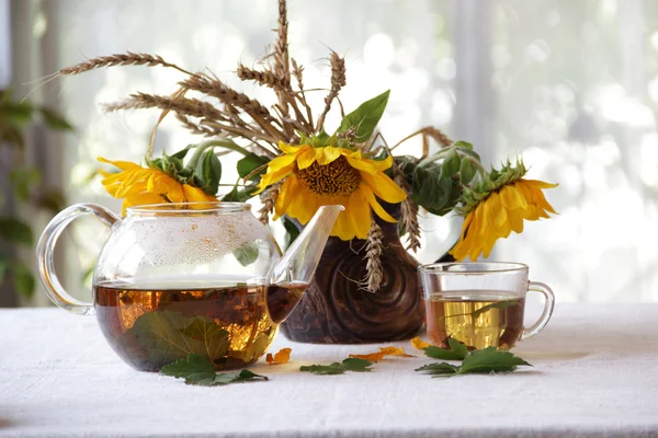 Чай у прозорому чайнику та соняшниках у керамічній вазі — стокове фото