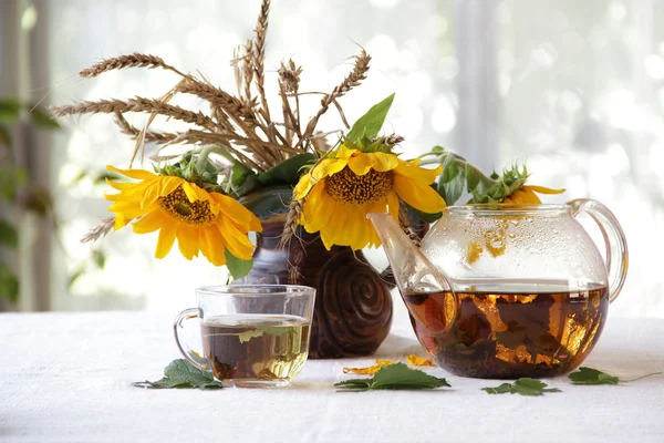 茶在一个透明的茶壶和陶瓷花瓶里的向日葵 — 图库照片