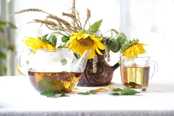 Натюрморт з чаєм в прозорому чайнику і букет сонця — стокове фото