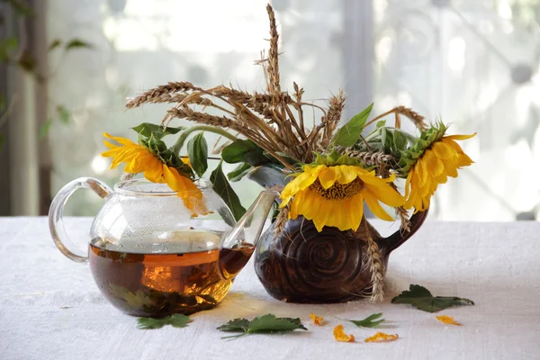 Чай в прозрачном чайнике и букет подсолнухов — стоковое фото