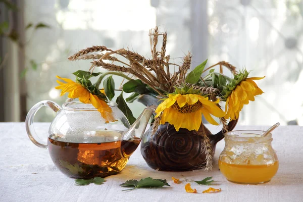 透明茶壶里的茶、蜂蜜和一束向日葵 — 图库照片