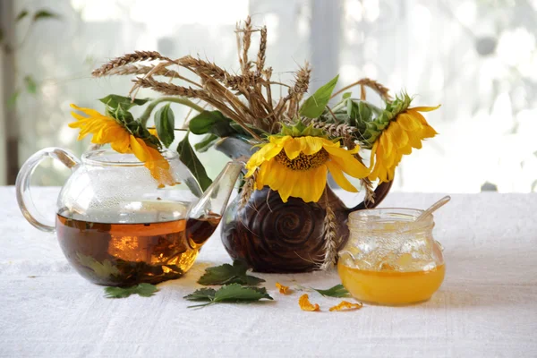 Tee in einer transparenten Teekanne und einem Strauß Sonnenblumen — Stockfoto