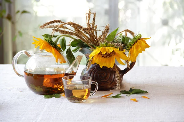 A tea egy átlátszó teáskanna és egy csokor nap csendélet — Stock Fotó