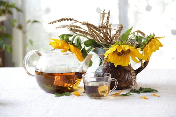 Натюрморт з чаєм в прозорому чайнику і букет сонця — стокове фото