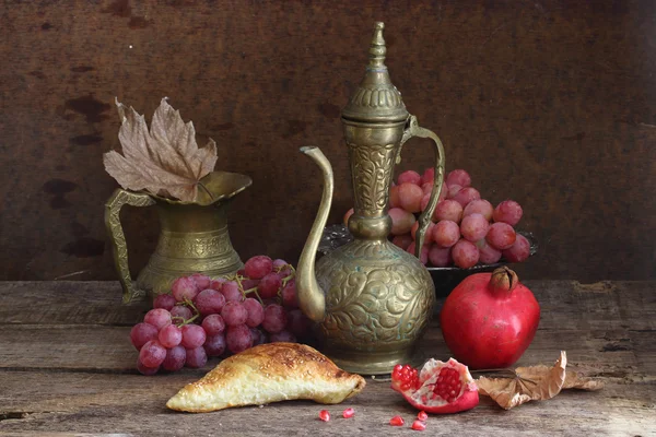 Nature morte avec une grenade, des raisins et une cruche en cuivre — Photo