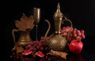 Bakır sürahi, kırmızı nar ve siyah bir adam üzerinde pembe üzüm