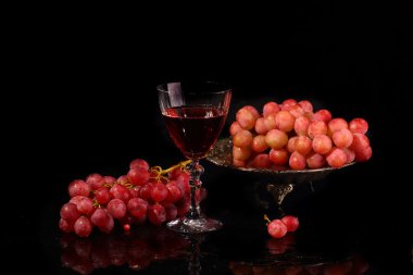 Cam ve pembe üzüm siyah bir zemin üzerine kırmızı şarap