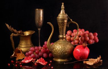 Bakır sürahi, kırmızı nar ve siyah bir adam üzerinde pembe üzüm