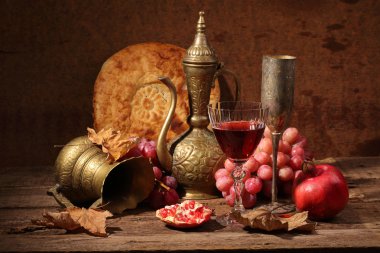 Still-life in east style with grapes, a pomegranate and a jug clipart
