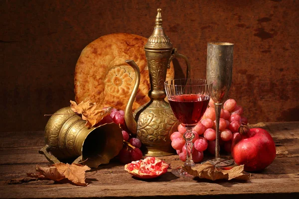 Still-life in east style with grapes, a pomegranate and a jug — Stock Photo, Image