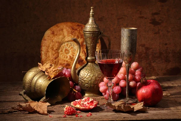 Still-life in east style with grapes, a pomegranate and a jug — Stock Photo, Image