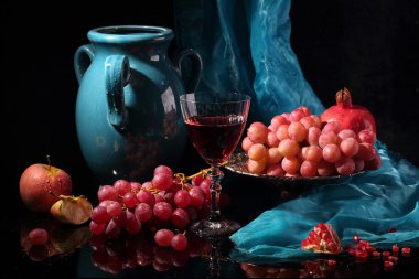 Kırmızı şarap, koyu mavi sürahi ve meyve siyah bir zemin üzerine