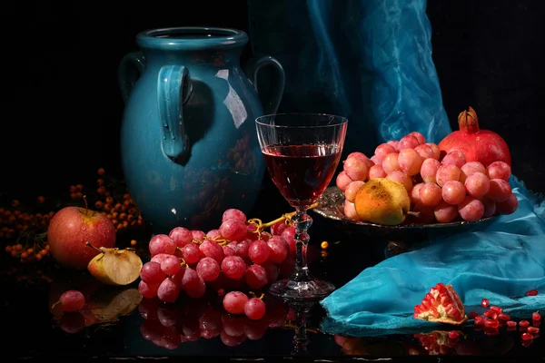 Rotwein mit Früchten und einem dunkelblauen Krug auf schwarzem Bac — Stockfoto