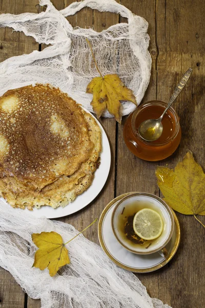 Tea with a lemon, pancakes, honey and autumn leaves — Stock Photo, Image