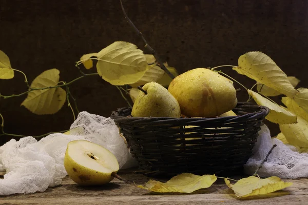 Poires dans un panier ondulé, noix et une branche d'un li d'automne — Photo