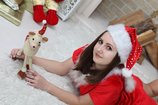 La ragazza in una causa di Babbo Natale contro un focolare su un albero di pelo — Foto Stock