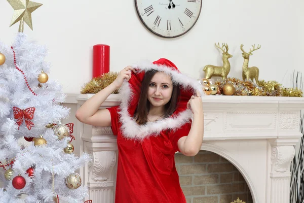 The girl in a suit of Santa Claus against a fireplace about a fu — Stock Photo, Image