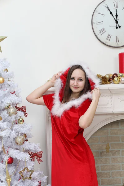 La ragazza in una causa di Babbo Natale contro un focolare su un fu bianco — Foto Stock
