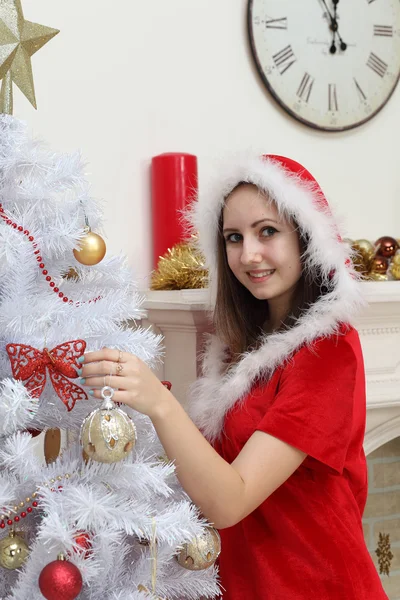 The girl in a suit of Santa Claus against a fireplace about a fu — Stock Photo, Image