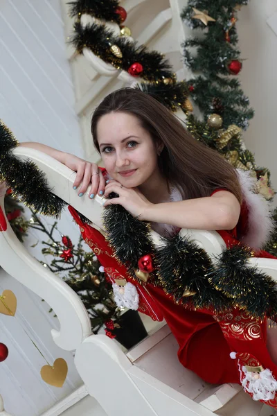 La ragazza in una causa di Babbo Natale su una scala bianca su un albero di pelo — Foto Stock