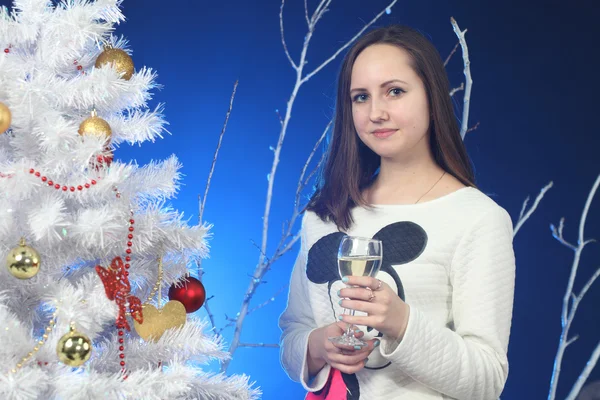 La muchacha con la copa de champán en las manos sobre el árbol de Año Nuevo —  Fotos de Stock