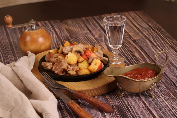 Roast with a potato, meat and mushrooms and a vodka wine-glass — Stock Photo, Image