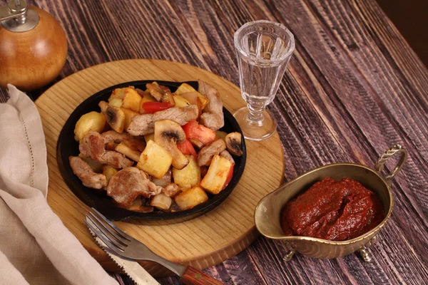 Roast with a potato, meat and mushrooms and a vodka wine-glass — Stock Photo, Image