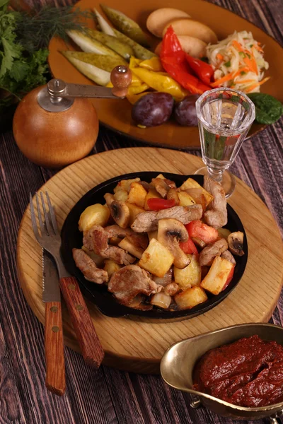 Assado com uma batata, carne e cogumelos e um copo de vinho de vodka — Fotografia de Stock