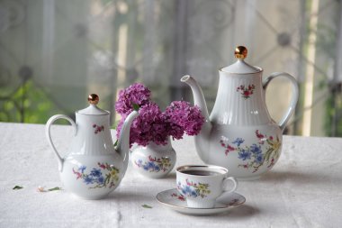 Bir bardak ve Lila bir buket bir tabloda çay