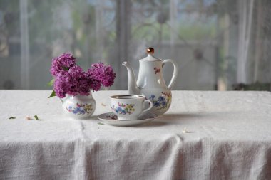 Bir bardak ve Lila bir buket bir tabloda çay