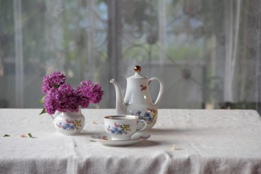 Bir bardak ve Lila bir buket bir tabloda çay