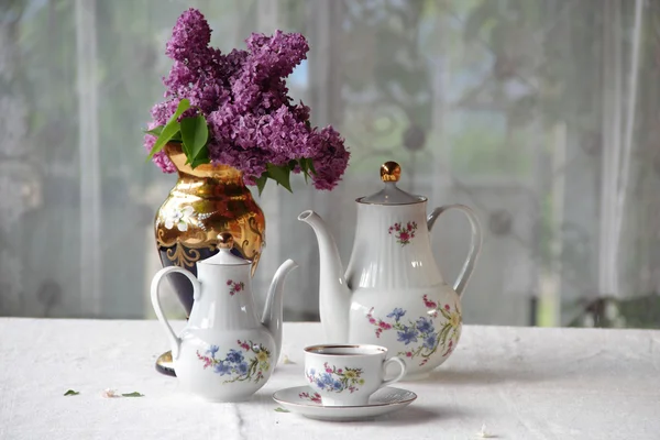 Chá em uma xícara e um buquê de lilás em uma mesa — Fotografia de Stock