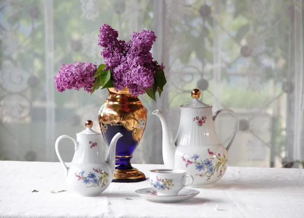 Tee in einer Tasse und ein fliederfarbener Strauß auf einem Tisch — Stockfoto