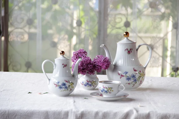 Tee in einer Tasse und ein fliederfarbener Strauß auf einem Tisch — Stockfoto