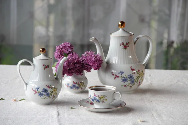 Thé dans une tasse, et un bouquet lilas sur une table — Photo