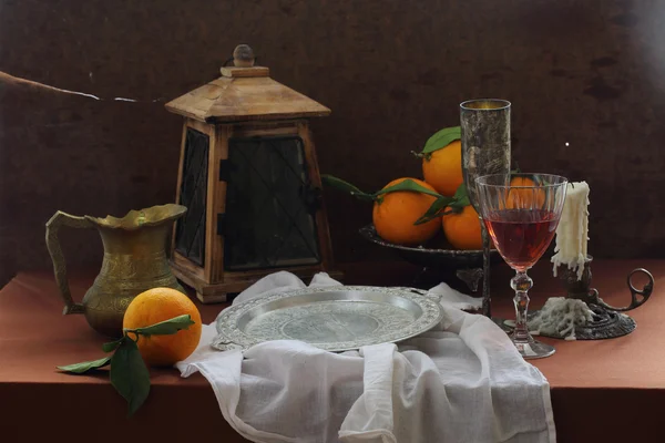Vinho em um copo transparente, laranjas e uma velha lanterna — Fotografia de Stock