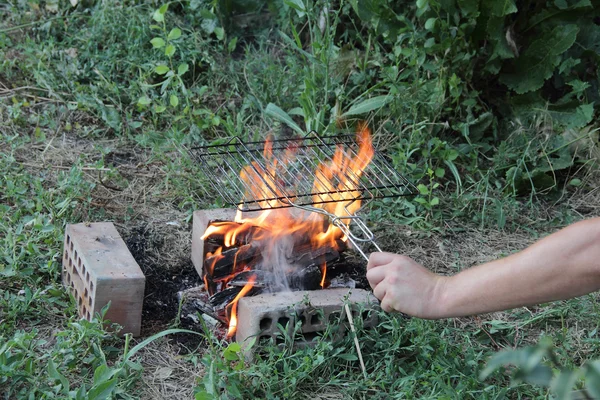 男子的手拿着一个格子, 放在火盆上烧烤 — 图库照片