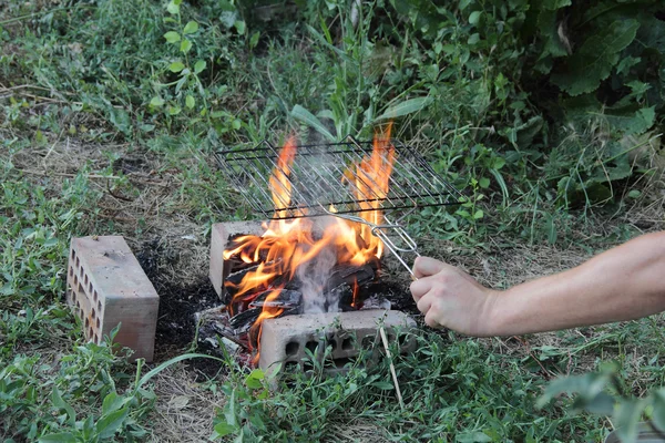 Ręka mężczyzny posiada kraty na grilla nad Kociołek — Zdjęcie stockowe